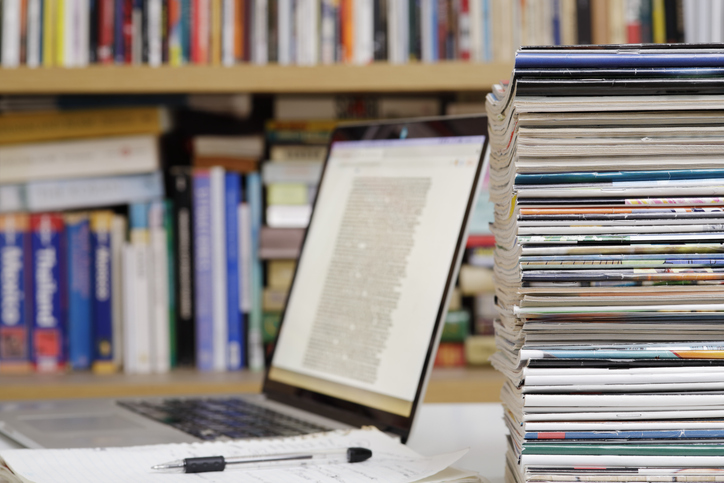 decorative laptop among some magazines and books on a shelf
