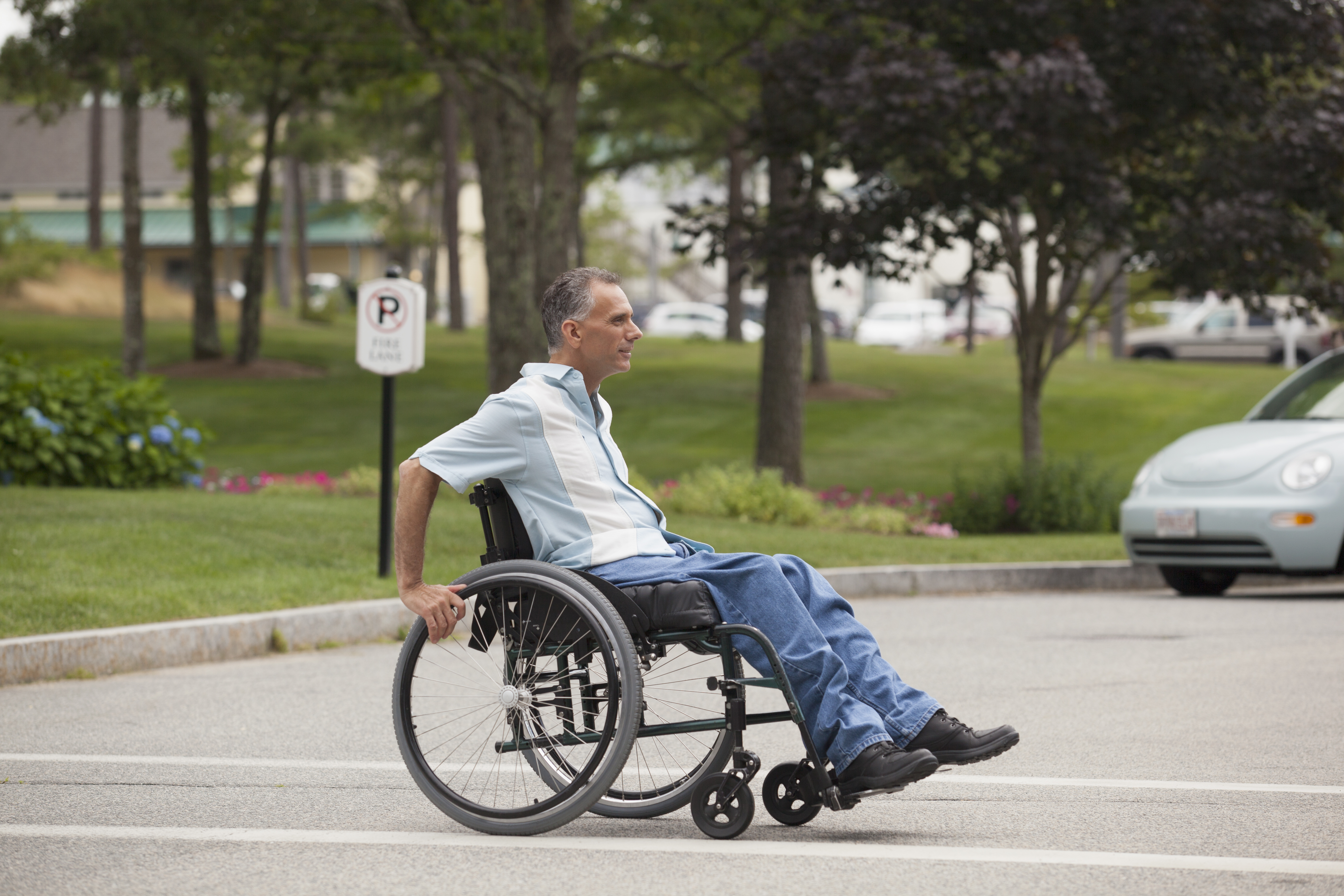 Man in wheel chair moving across parking lot