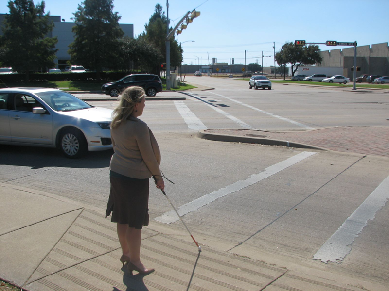 This is an image of a visually impaired woman waiting to cross the street.