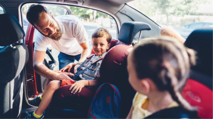 a father buckling two children into car seats